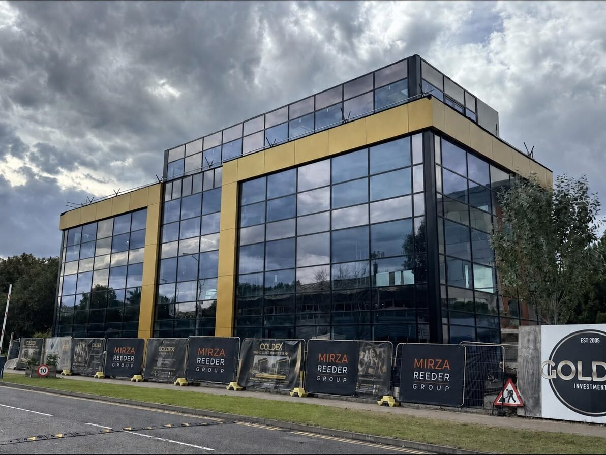 The Goldex headquarters under construction: a glazed office building with gold-clad columns, behind Mirza Reeder Group site hoarding